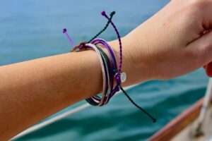 Colorful string bracelets on a wrist by the water.